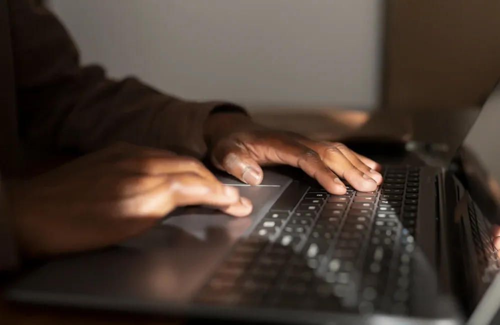 Manos de una persona escribiendo en el teclado de un computador portátil