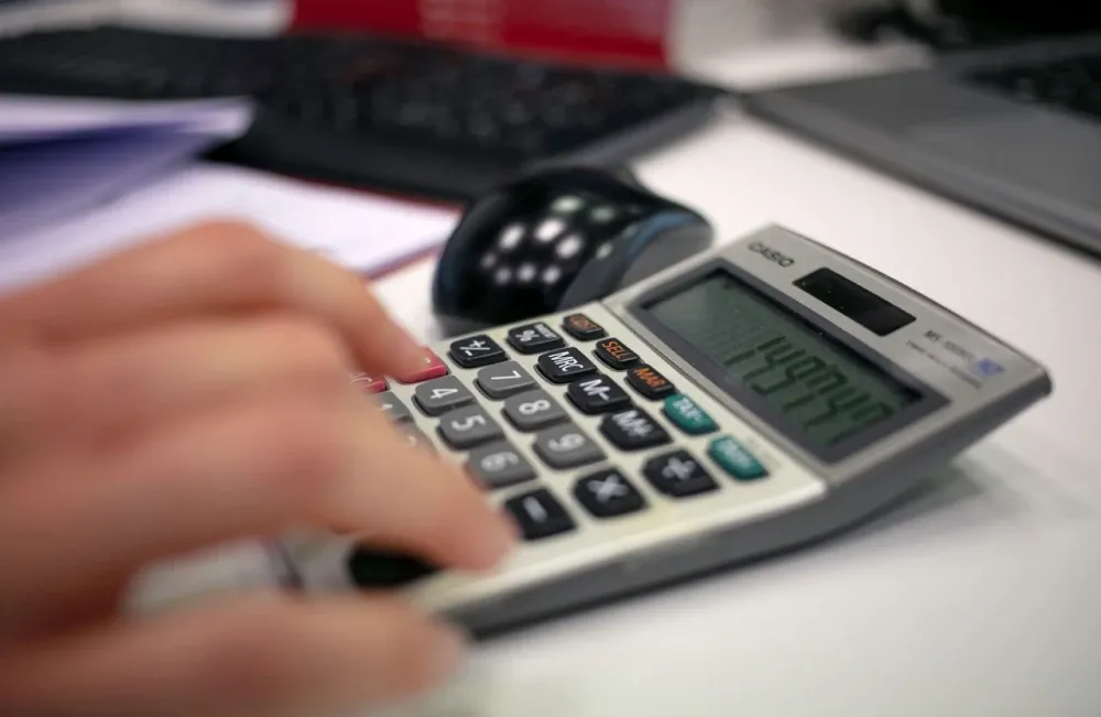 Mano de una persona usando una calculadora sobre un escritorio de oficina