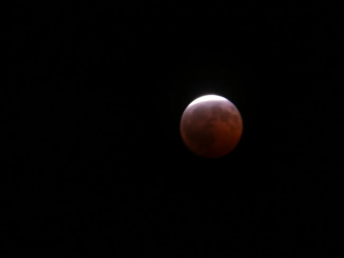 La Luna durante un eclipse lunar, con una parte de su superficie en sombra y tonos rojizos