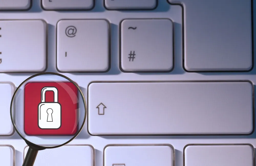 Lupa sobre una tecla roja con un candado en un teclado de computador